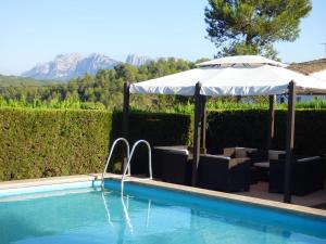 einen Pool mit Sonnenschirm und Stühlen in der Unterkunft Luxurious Cottage in Sant Salvador de Guardiola in Guardiola