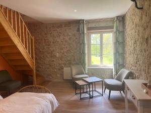 a bedroom with a staircase and a bed and chairs at Le Moulin de Moquesouris - Chambres d'hôtes et table d'hôte in Nazelles