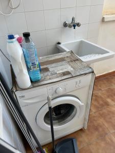 a washing machine with a sink and bottles of detergent at Carolina apartamento de Luxe in Mazarrón