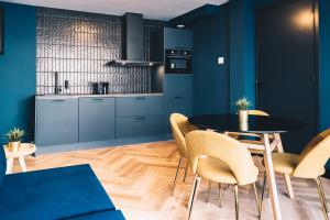 een keuken met blauwe kasten en een tafel en stoelen bij LVM Stays in Den Haag