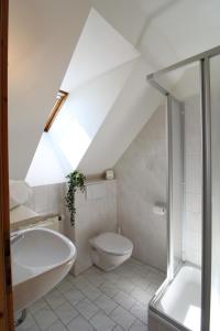 a white bathroom with a toilet and a bath tub at Landhaus Nockalm in Bad Kleinkirchheim
