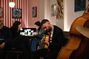 mężczyzna w garniturze i krawacie grający na gitarze w obiekcie D8 - Shoreditch w Londynie