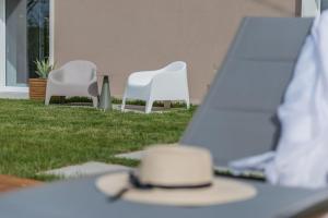 Duas cadeiras brancas e uma mesa com um chapéu. em Villa Gea 12 em Fermignano