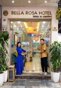 un hombre y una mujer parados frente a un hospital en Bella Rosa Hotel & Travel en Hanoi