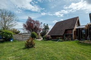 a house with a grass yard next to a building at Le Chalet Boisé - Maison avec jardin clôturé in Montoldre +7 photos
