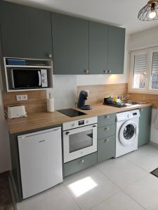 a kitchen with green cabinets and a washer and dryer at Chez Ernestine in Nanteuil-lès-Meaux