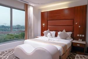 una camera da letto con un grande letto bianco con una grande finestra di شقق فربيون الفندقية -محايل a Muhayil
