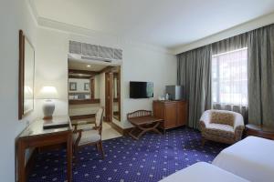 a hotel room with a desk and a bedroom at The Jesselton Hotel in Kota Kinabalu