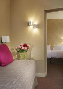 a bedroom with a bed with a vase of flowers on a table at Hôtel Londres et New York - Teritoria in Paris