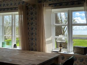 a room with two windows and a table with a lamp at Huus Hannchen in Langeneß