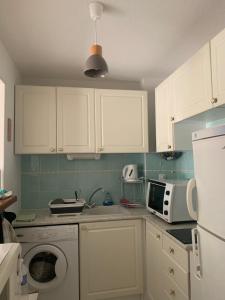 - une cuisine avec des placards blancs et un lave-linge dans l'établissement Le Tropical, à Fréjus