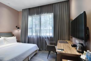 Habitación de hotel con cama y escritorio con TV. en The Jesselton Hotel en Kota Kinabalu