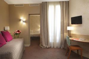 a hotel room with a bed and a desk and a window at Hôtel Londres et New York - Teritoria in Paris