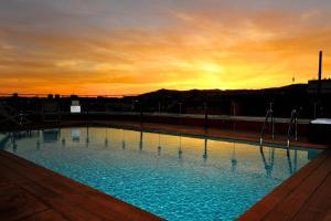 a large swimming pool with a sunset in the background at Hotel 1898 in Barcelona