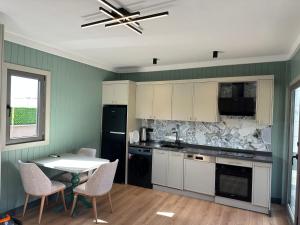 a kitchen with white cabinets and a table with chairs at Premium park rezidans in Kemer