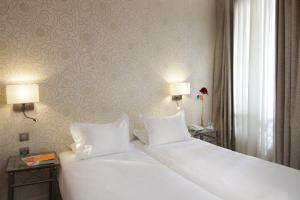 a bedroom with a large white bed with two lamps at Hôtel Londres et New York - Teritoria in Paris