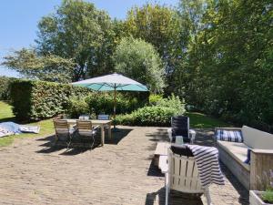 a patio with a table and chairs and an umbrella at Charmant vakantiehuis op unieke locatie in Groede