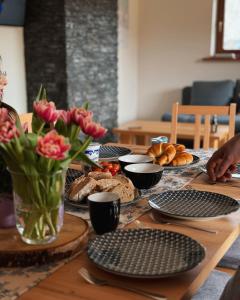 een tafel met borden, bloemen en brood erop bij Apartamenty na Soszowie, Wisła - widokowe miejsce z Balią & Prywatną Sauną, obok stoku narciarskiego i Bike Parku, dla max 16 osób in Wisła +107 foto's