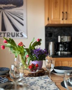 a table with glasses and a vase with flowers on it at Apartamenty na Soszowie, Wisła - widokowe miejsce z Balią & Prywatną Sauną, obok stoku narciarskiego i Bike Parku in Wisła