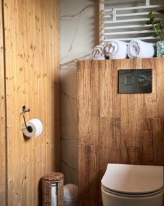 a bathroom with a toilet and towels on a wooden wall at Apartamenty na Soszowie, Wisła - widokowe miejsce z Balią & Prywatną Sauną, obok stoku narciarskiego i Bike Parku in Wisła