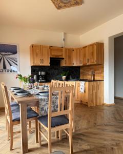 a kitchen with wooden cabinets and a table with chairs at Apartamenty na Soszowie, Wisła - widokowe miejsce z Balią & Prywatną Sauną, obok stoku narciarskiego i Bike Parku in Wisła