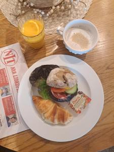 Un plato blanco con un sándwich y una taza de café. en Hotell Rådhuset en Lidköping