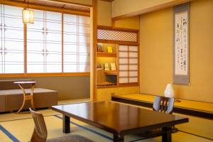 Pokój ze stołem, krzesłami i oknem w obiekcie Saginoyusou w mieście Yasugi