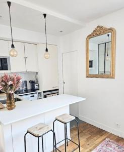 uma cozinha branca com um balcão e dois bancos em L'atelier, T3 central, calme et charme em Vincennes