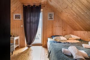 a bedroom with wooden walls and a large window at Domek wczasowy z dostępem do Mini zoo Donkeyszot 