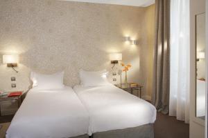 a bedroom with a large white bed with two pillows at Hôtel Londres et New York - Teritoria in Paris