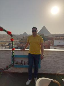 Ein Mann steht auf einem Felsvorsprung mit Blick auf Pyramiden. in der Unterkunft Golden pyramids view in Kairo