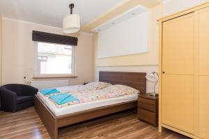 a bedroom with a bed and a chair and a window at Holiday House BURSZTYN - Nature, Relax & Terrace by Noclegi Renters in Kołczewo
