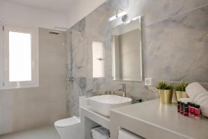 W łazience znajduje się umywalka, toaleta i lustro. w obiekcie Defamelia Villa w mieście Kefalonia