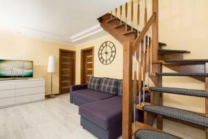 a living room with a purple couch and stairs at Holiday House BURSZTYN - Nature, Relax & Terrace by Noclegi Renters in Kołczewo