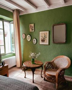 a green bedroom with a table and a chair and a mirror at Chez Rosette de Lussan in Lussan