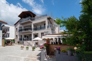 a large white building with tables and umbrellas at Irene's House Kalamitsi in Kalamitsi