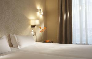 a bedroom with a bed with white sheets and a window at Hôtel Londres et New York - Teritoria in Paris