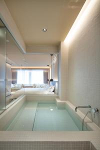 a bathroom with a tub with a bed in the background at HotelCO Kuramae ホテル コ 蔵前 in Tokyo