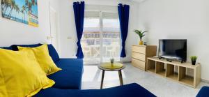 Una sala de estar con un sofá azul y un televisor. en Sunny Penthouse close to everything, en Torrevieja