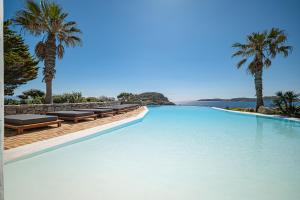 una gran piscina con sillas y palmeras en Sanarte Villas Mykonos en Mykonos