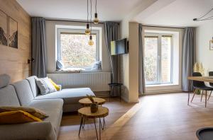 a living room with a couch and two windows at Apartmány Mýtinka - Jeseníky in Jeseník