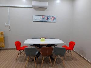 a meeting room with a white table and red chairs at K.Cottage in Muar