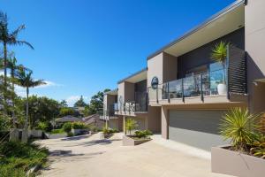 a house with palm trees in front of it at Stylish 4BR Retreat with Water Views in Port Macquarie