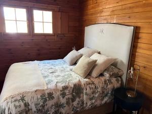 a bedroom with a bed with wooden walls and windows at EL BOSQUE ENCANTADO in La Estación