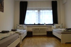 two beds in a room with a window and a radiator at Maye Oberhausen City Deluxe 3 in Oberhausen
