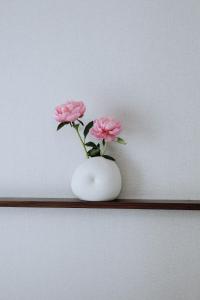 a white vase with pink flowers on a shelf at Hôtel Londres et New York - Teritoria in Paris
