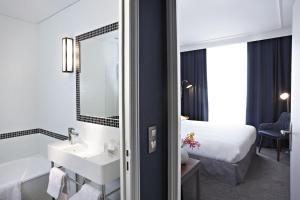 a bathroom with a sink and a mirror and a bed at Hôtel Londres et New York - Teritoria in Paris