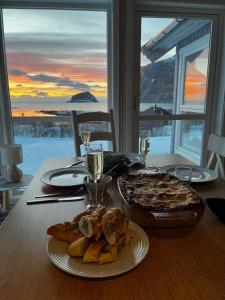 una mesa con un plato de comida y una pizza en Cabin Panorama Lofoten with Jacuzzi Magic view, en Offersøya