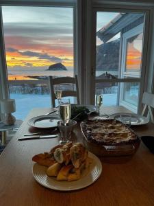 a table with a plate of food and a pizza at Cabin Panorama Lofoten with Jacuzzi Magic view in Offersøya