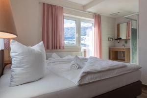 Cama blanca con almohadas blancas y ventana en Pitztal Living en Jerzens